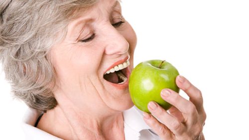 Portrait of senior woman holding an apple and eating it   Note to inspector: the image is pre-Sept 1 2009